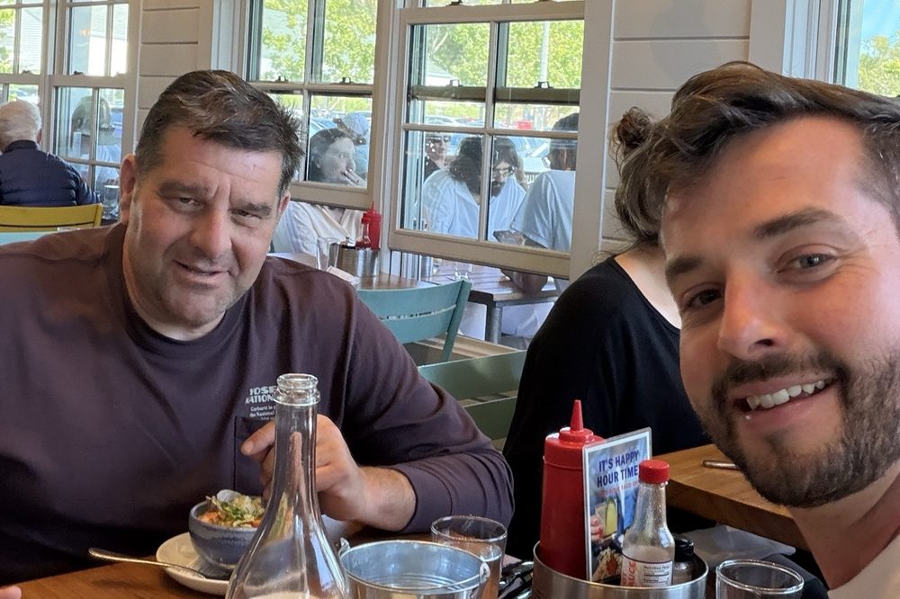 Joe Riccuci and Tom Loebenstein at a table in a sunlit restaurant, mid-lunch.